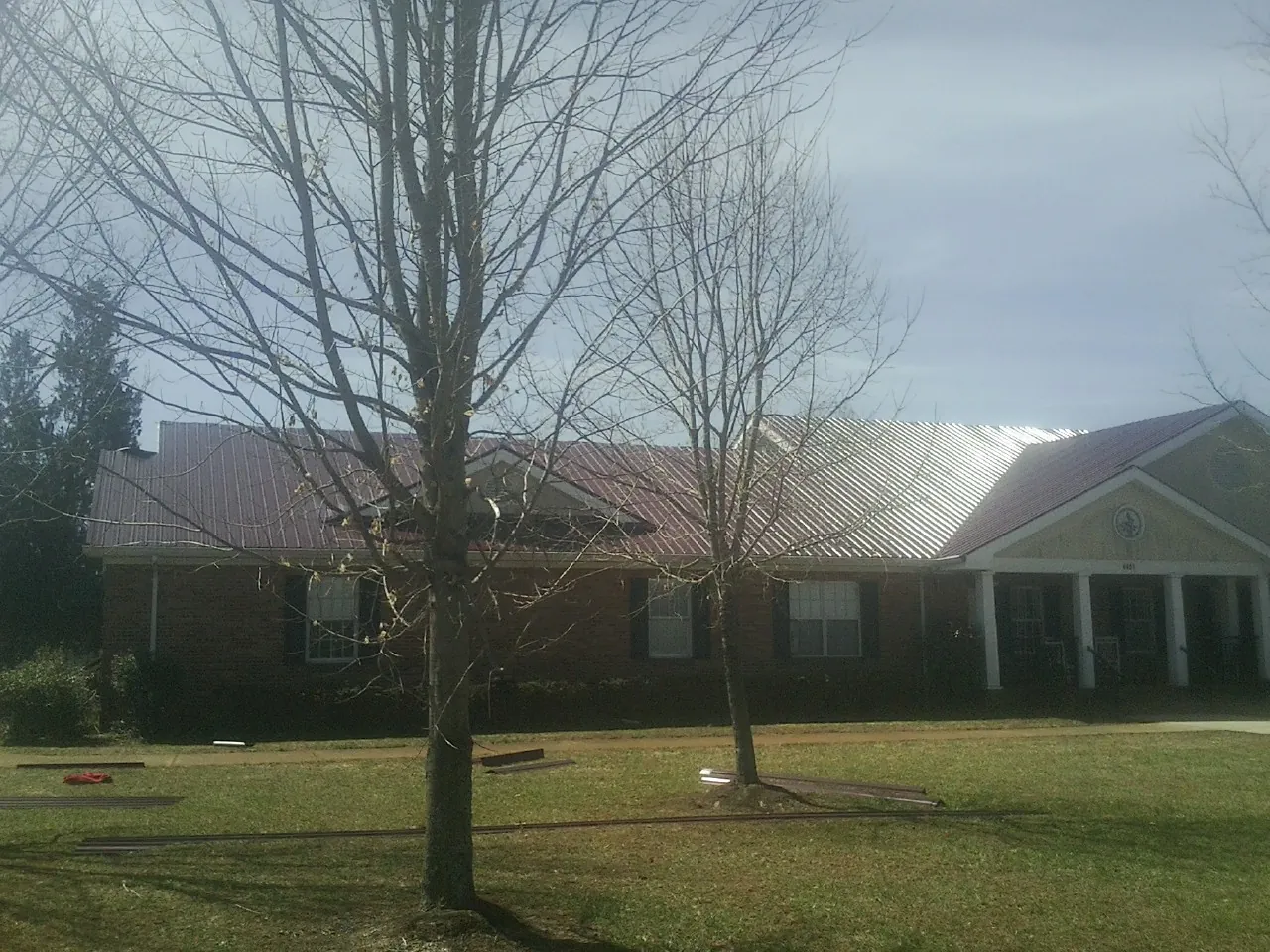 Red metal roof on a brick building seen from the front lawn in Converse