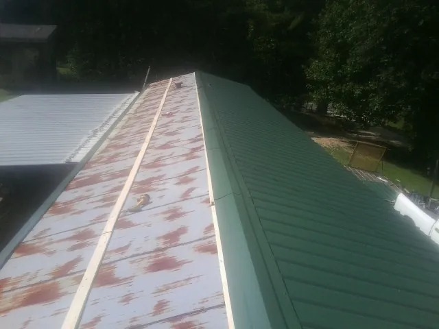 Old rusted panels beside newly installed green metal roofing — Wind Damage Roof Repair by Roofing Brothers in Converse